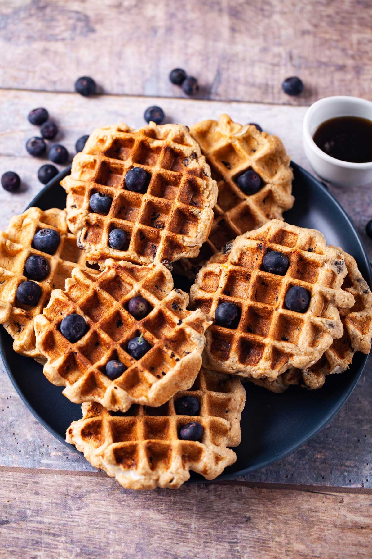 Oat flour waffles on a plate topped with blueberries.