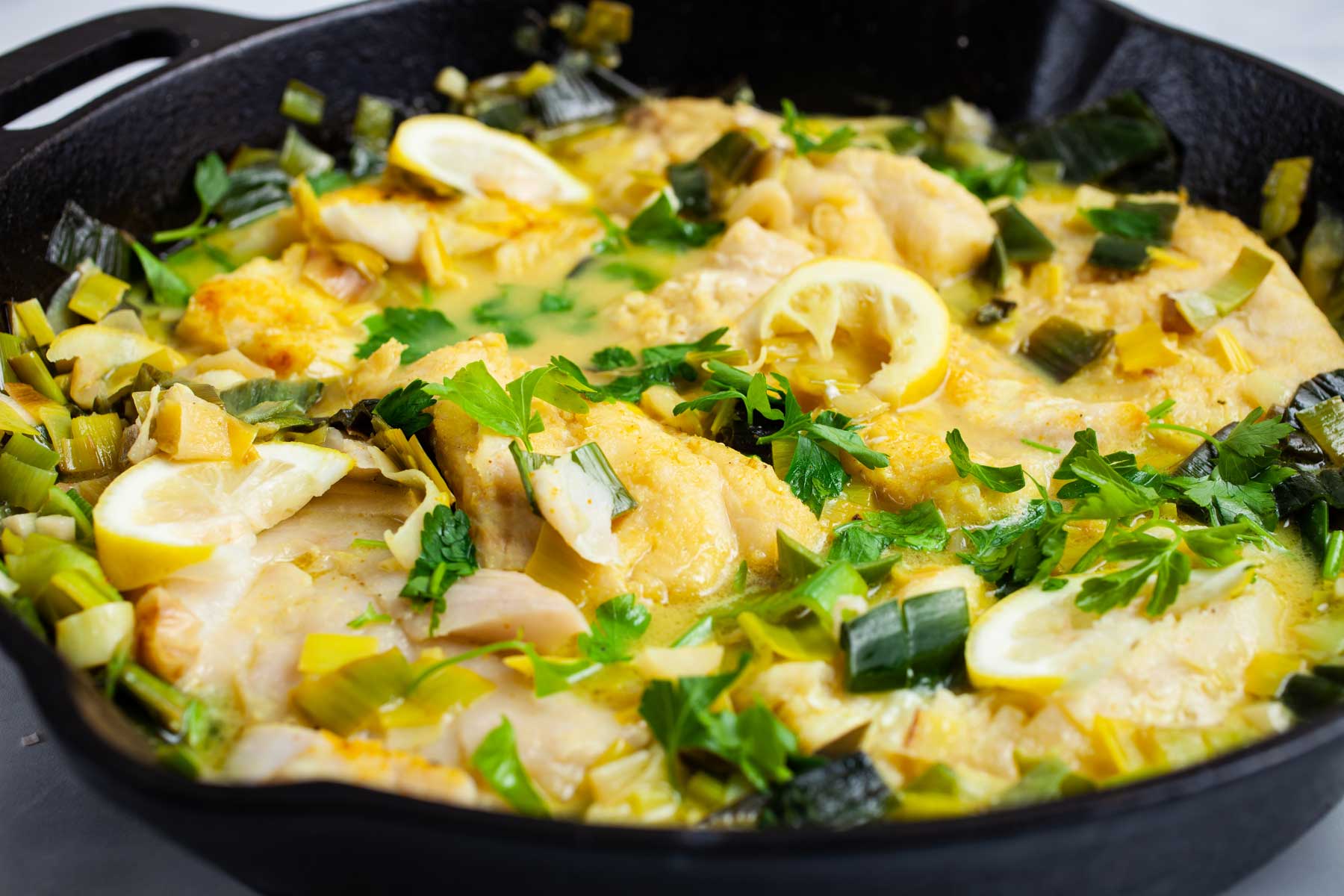 Creamy cooked cod and leek in a pan.