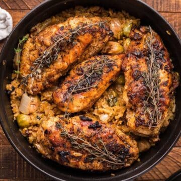 Baked chicken in a cast iron pan with rice and Brussels sprouts.