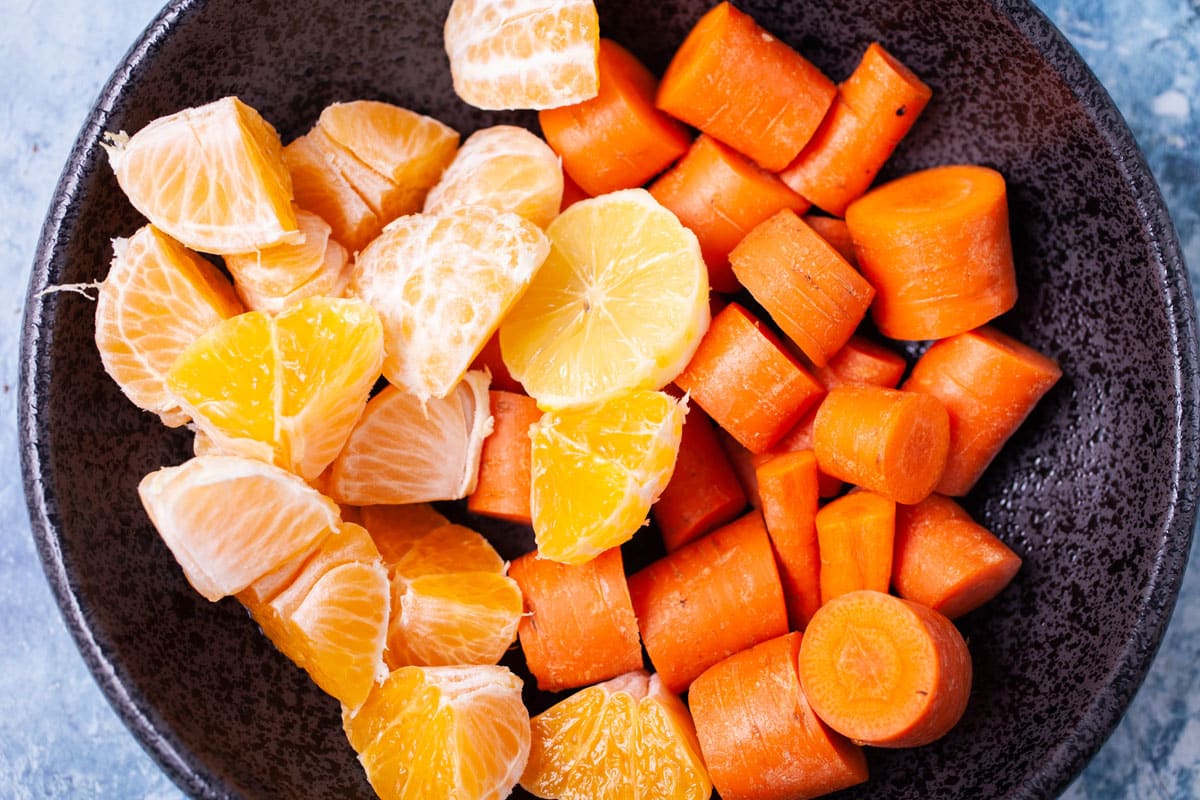 Chopped carrots, oranges and half a lemon in a serving board.