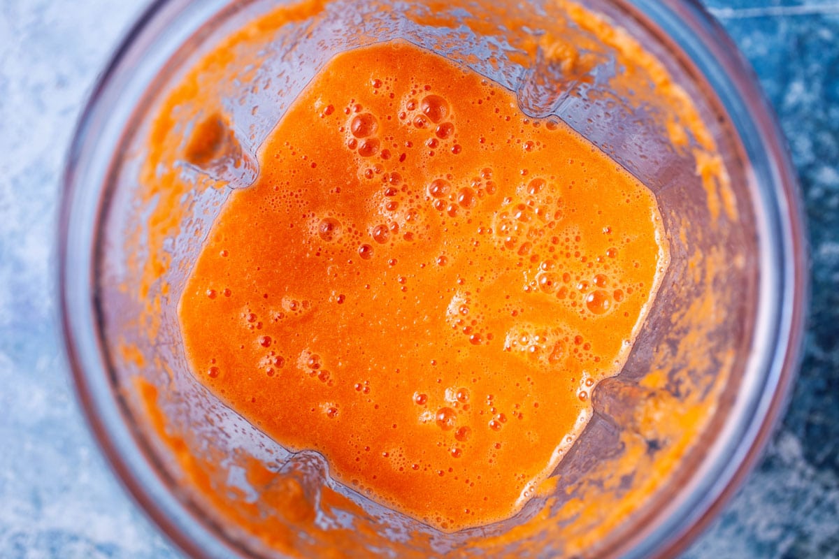 An orange smoothie in a blender.