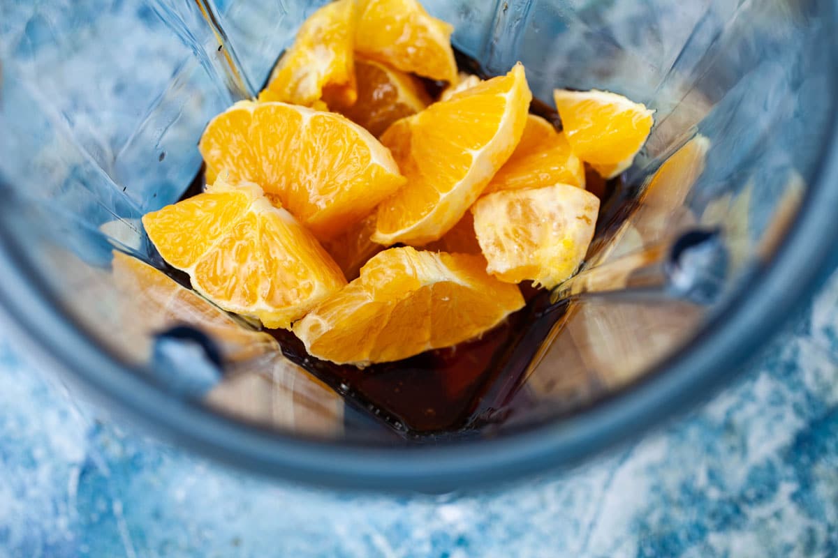Sliced oranges and maple syrup in a blender.
