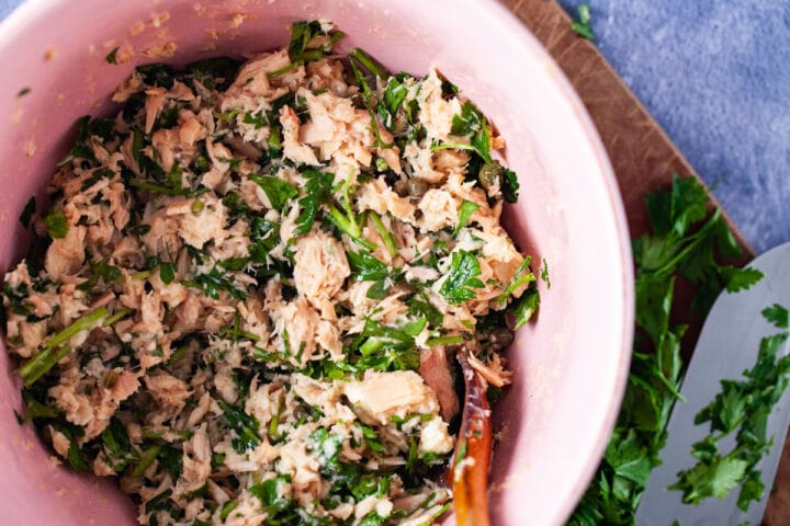 A bowl filled with canned tuna and fresh parsley salad.