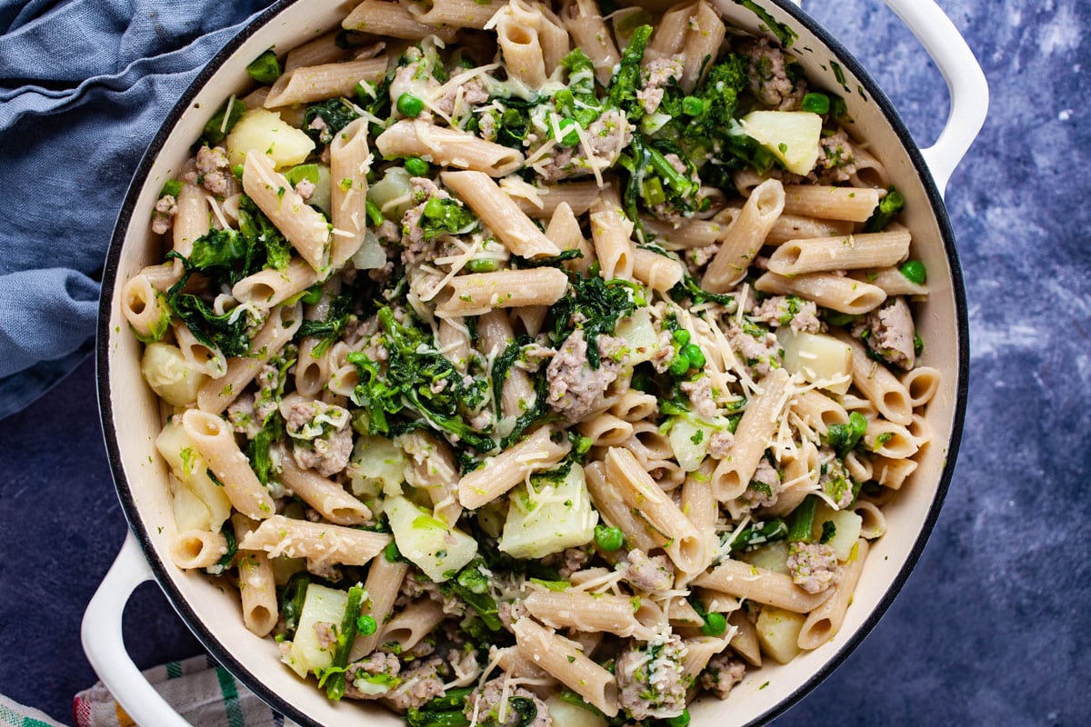 A large Dutch oven pan filled with sausage and broccoli rabe pasta.