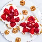 Two toasts on a plate with peanut butter, cottage cheese, fresh berries and a drizzle of honey.