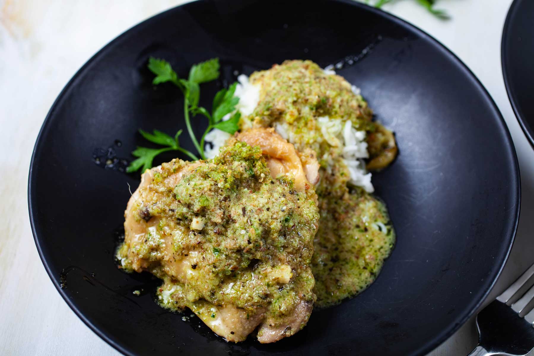 Pan-seared chicken on top of cooked rice and topped with a pesto sauce.