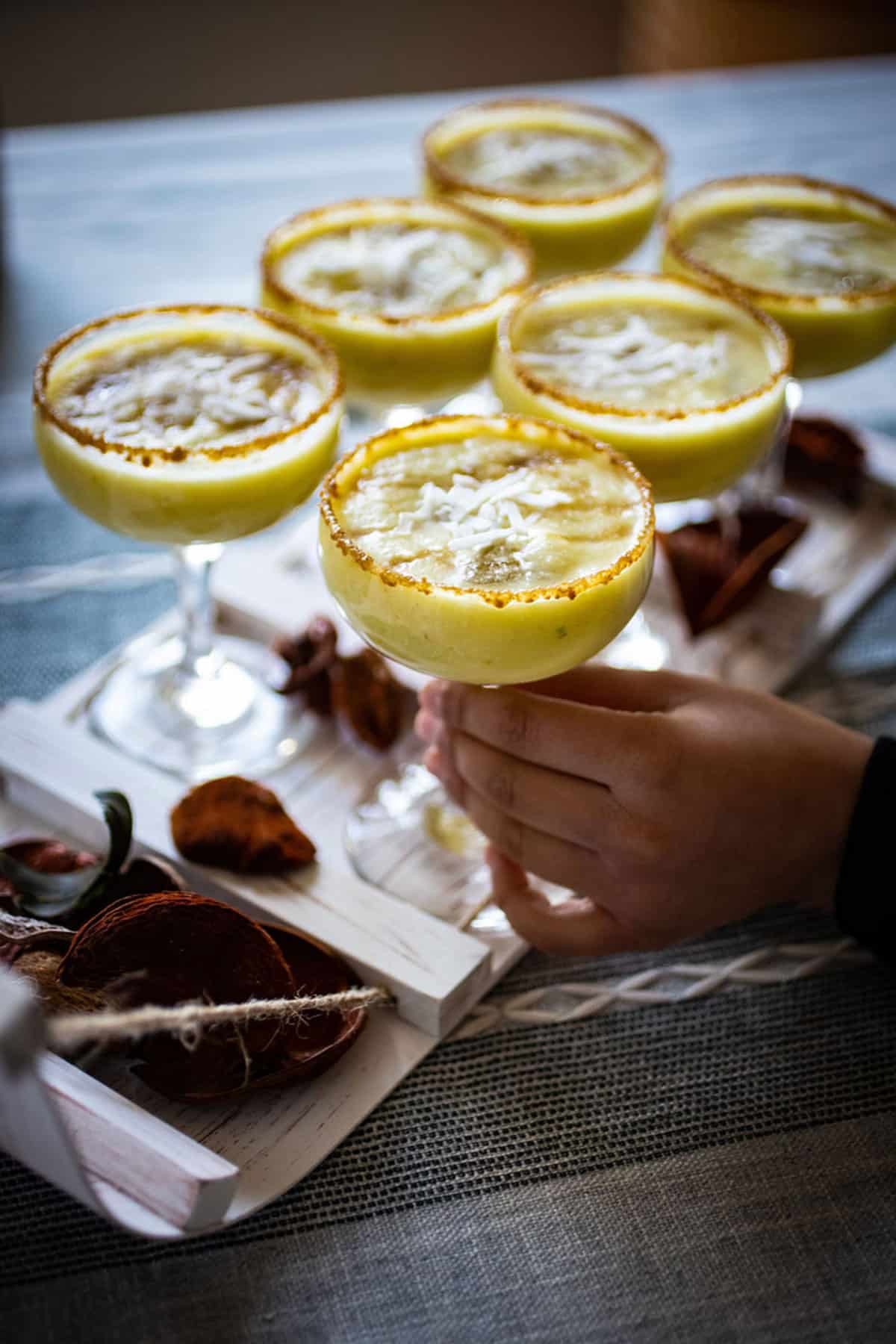 A child's hand taking a pina colada mocktail off a tray.