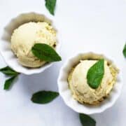 Two small bowls with pineapple avocado ice cream and topped with fresh mint leaves.