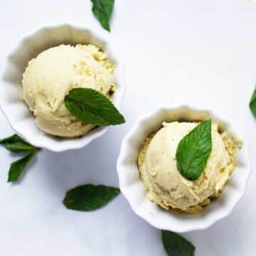 Two small bowls with pineapple avocado ice cream and topped with fresh mint leaves.