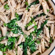 A garlic spinach pasta recipe with peas in a large Dutch pan topped with Parmesan Cheese.