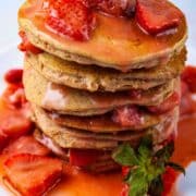 A stack of plantain pancakes tipped with a strawberry sauce.