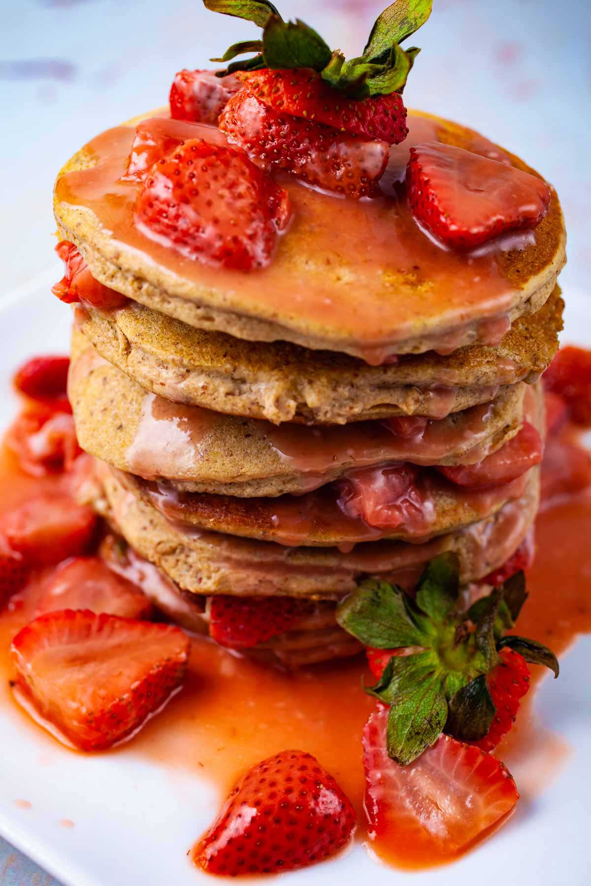 A stack of plantain pancakes tipped with a strawberry sauce.