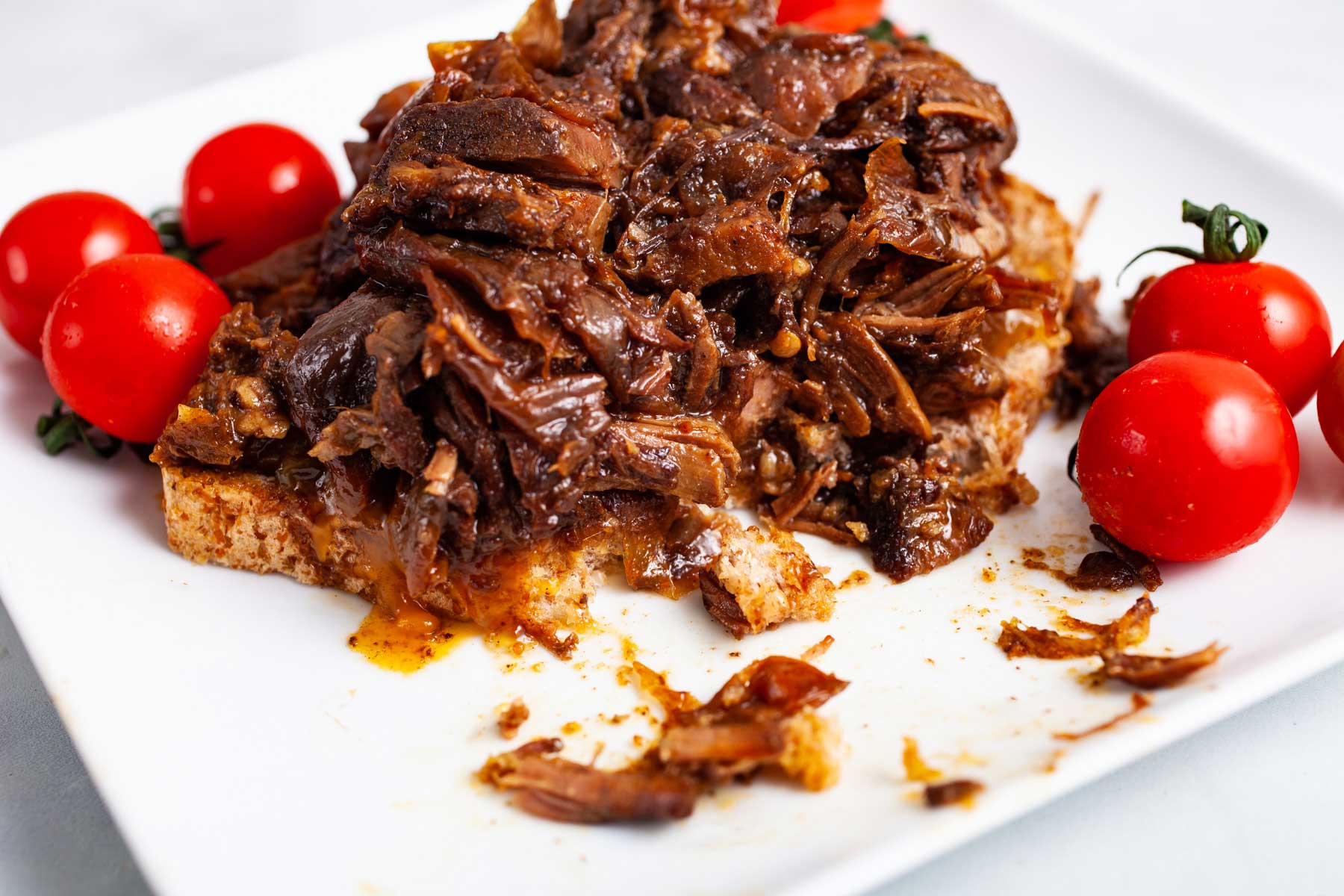Leftover pot roast on a sandwich served with tomatoes.