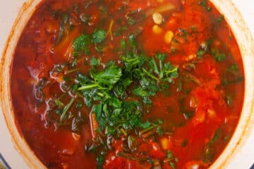 Chopped parsley added to a vegetable soup in a Dutch pan.