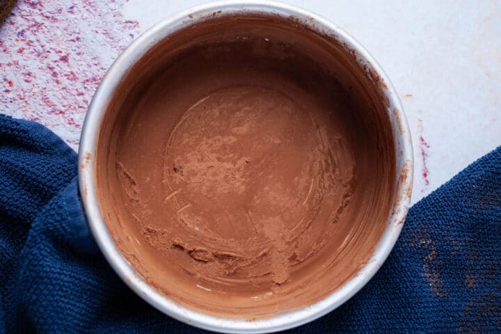 A small baking pan with its sides greased with butter and coated with cacao powder.