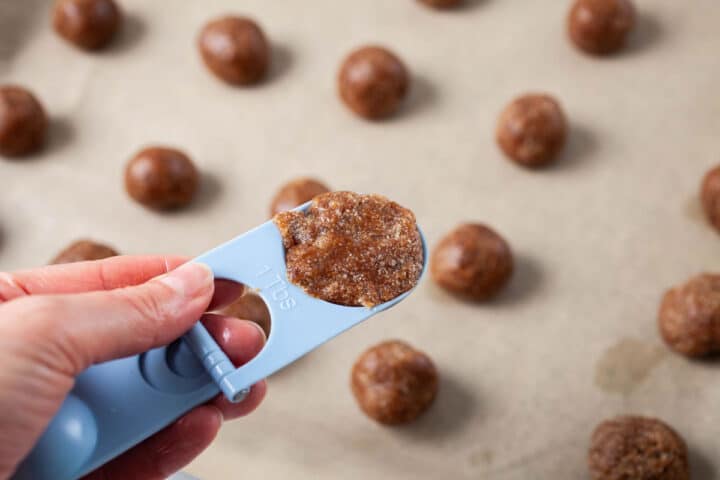 Someone holding a tablespoon of cookie dough in hand.