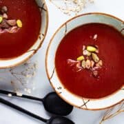 Purple soup served in bowls and garnished with nuts.