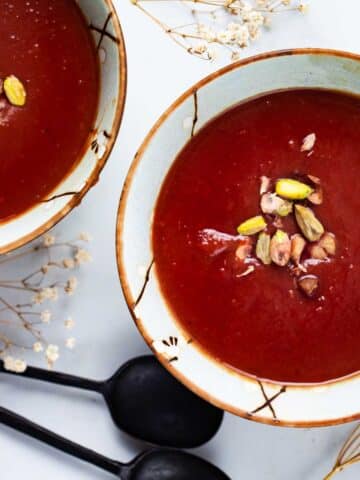 Purple soup served in bowls and garnished with nuts.