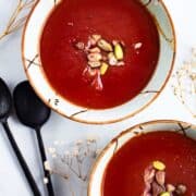 Purple soup served in bowls and garnished with nuts.