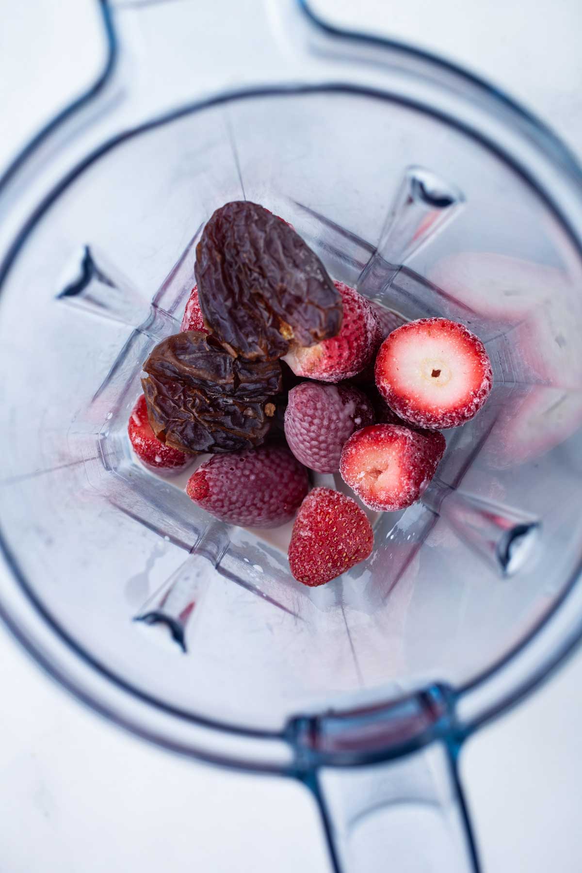 Frozen strawberries, dates and milk in a blender.