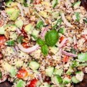 Cucumber quinoa salad with a creamy dressing tossed in. a wooden bowl.