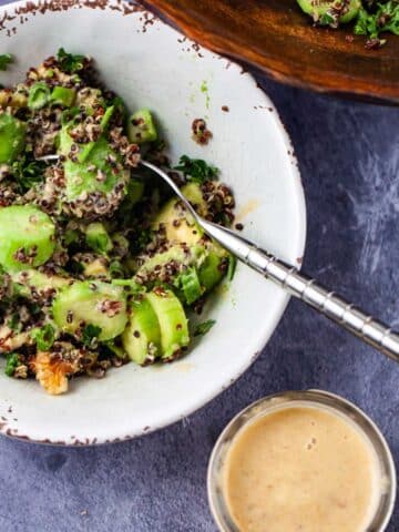 A small bowl filled with avocado quinoa salad and a creamy lemon dressing on the side.