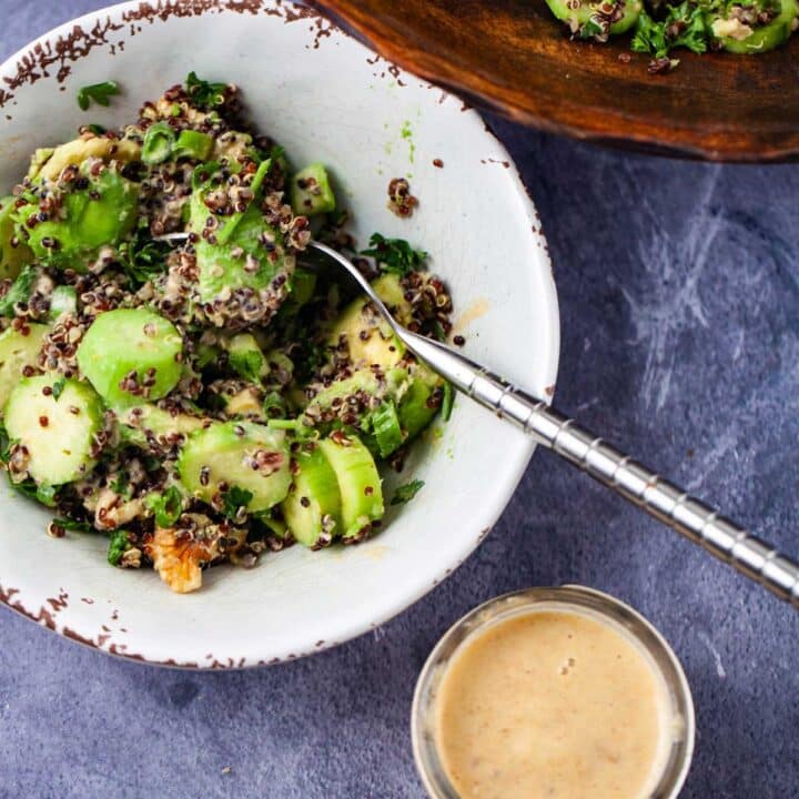 A small bowl filled with avocado quinoa salad and a creamy lemon dressing on the side.