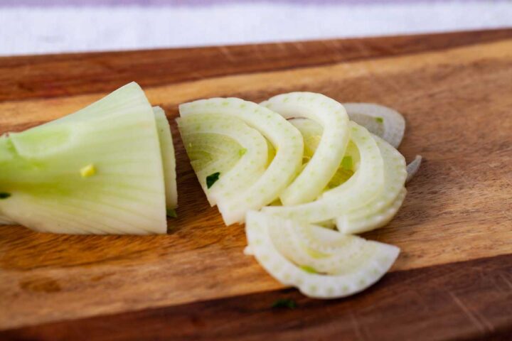 Thinly sliced fennel on a wooden board.