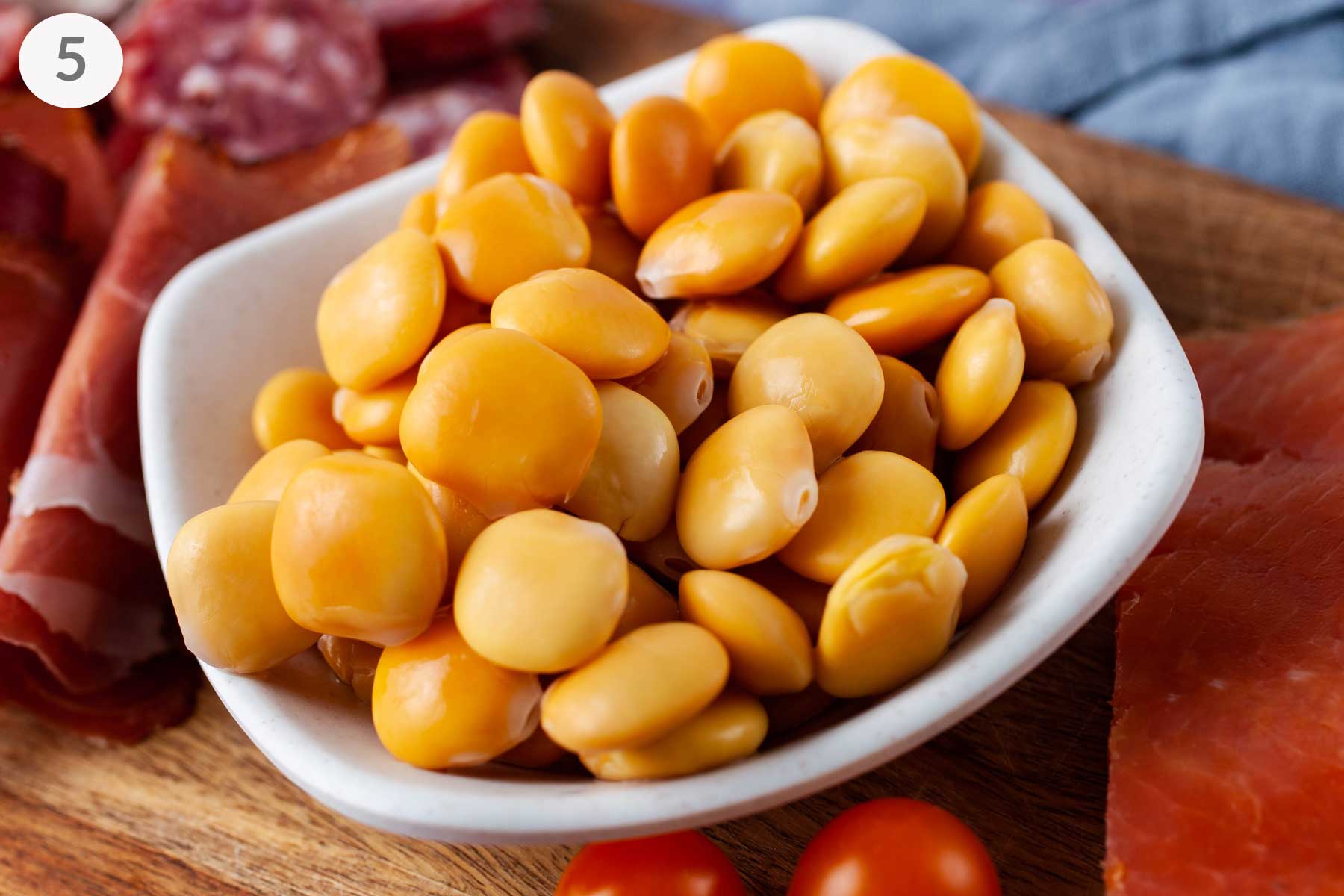 A small bowl with prepared Lupini beans displayed on a charcuterie board.