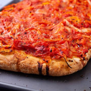 A thick crusted pizza with spicy red sauce onion toppings.