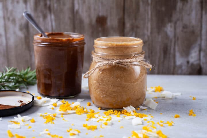 Two jars of different flavored nut butters against a wooden back drop.