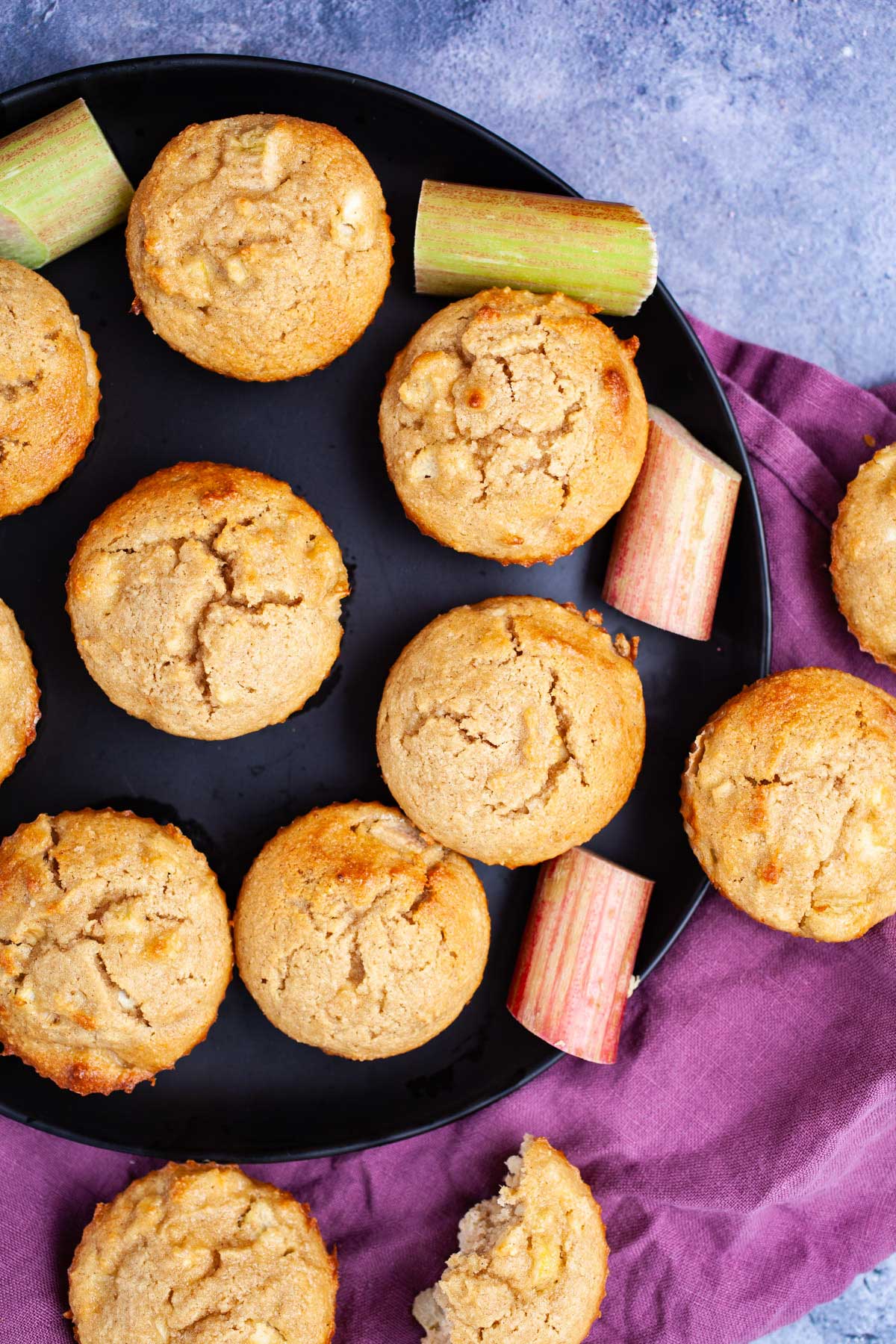 Rhubarb muffins displayed on a plate and some on the table.