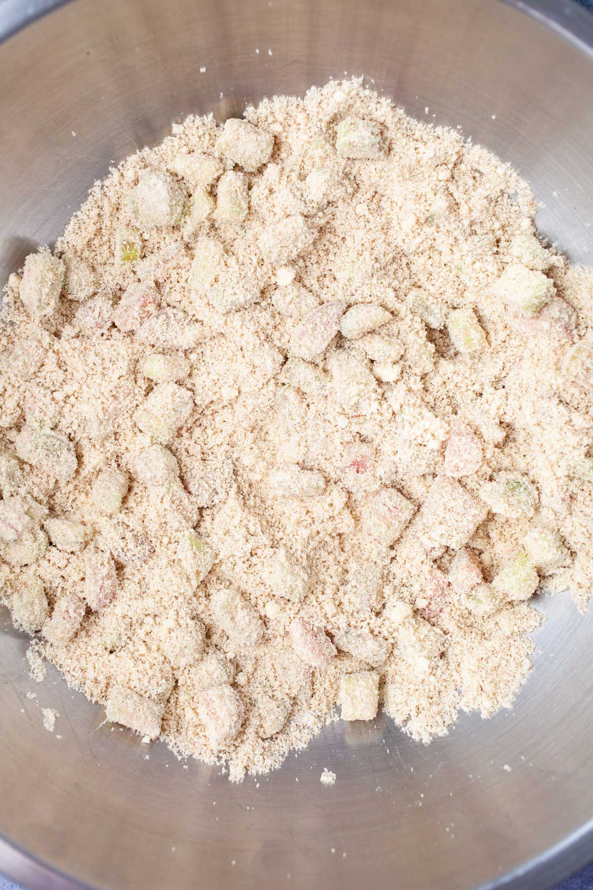 Pieces of rhubarb coated with almond flour in a large bowl.