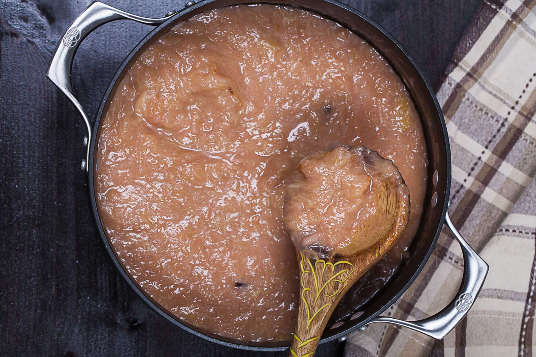 A wooden spoon resting on top of a thick compote in a pot.