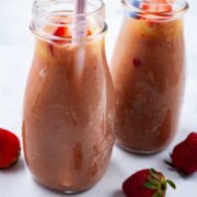 Two rhubarb smoothies in glass jars with straws.