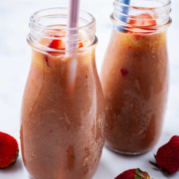 Two rhubarb smoothies in glass jars with straws.