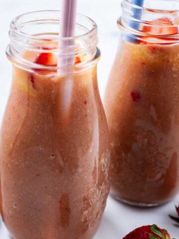 Two rhubarb smoothies in glass jars with straws.