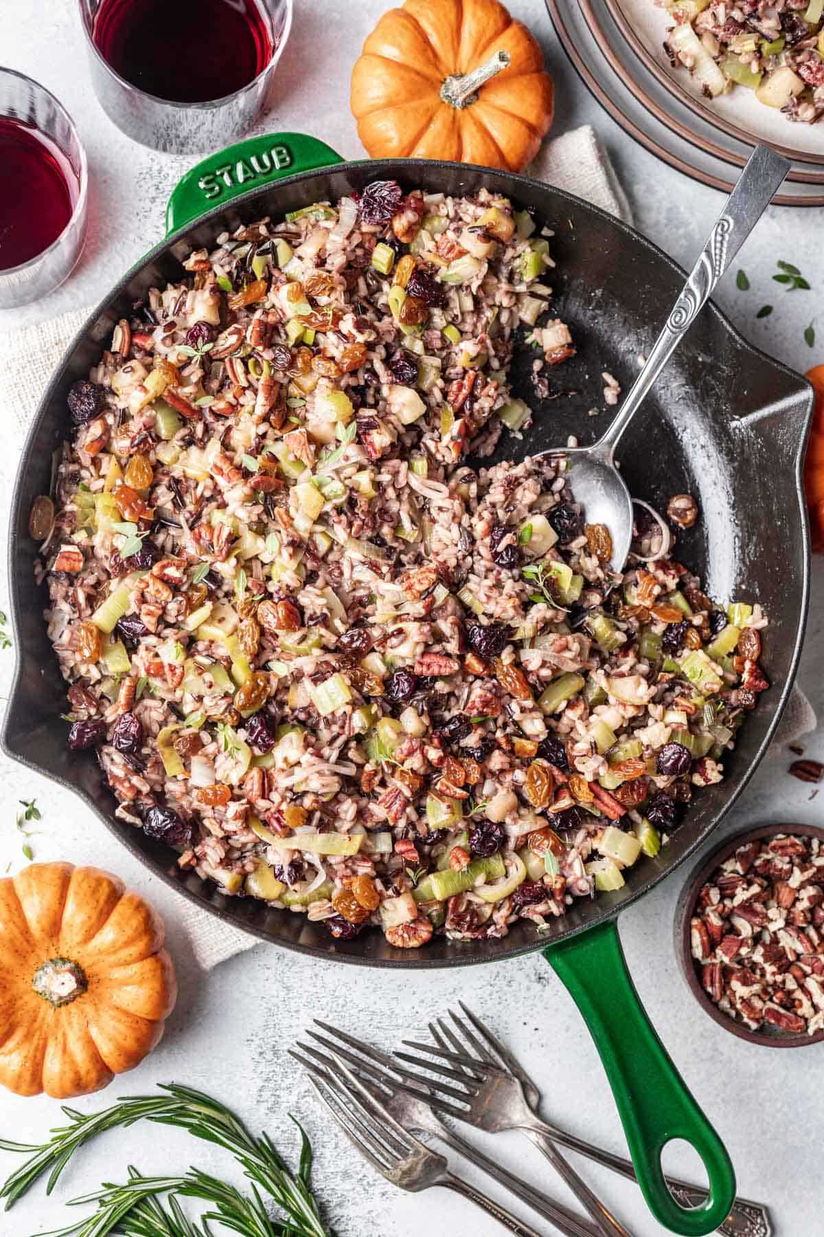 A spoon resting in a cast-iron pan with Thanksgiving rice dish.
