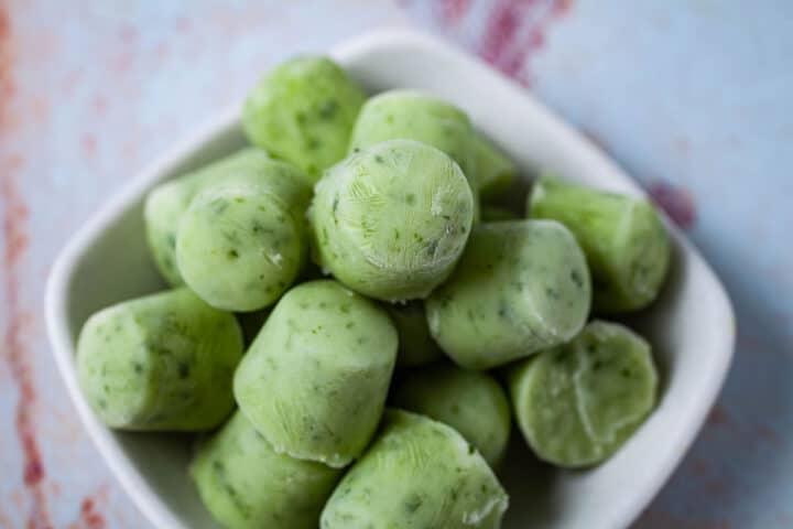 A small bowl filled with green ice cubes.