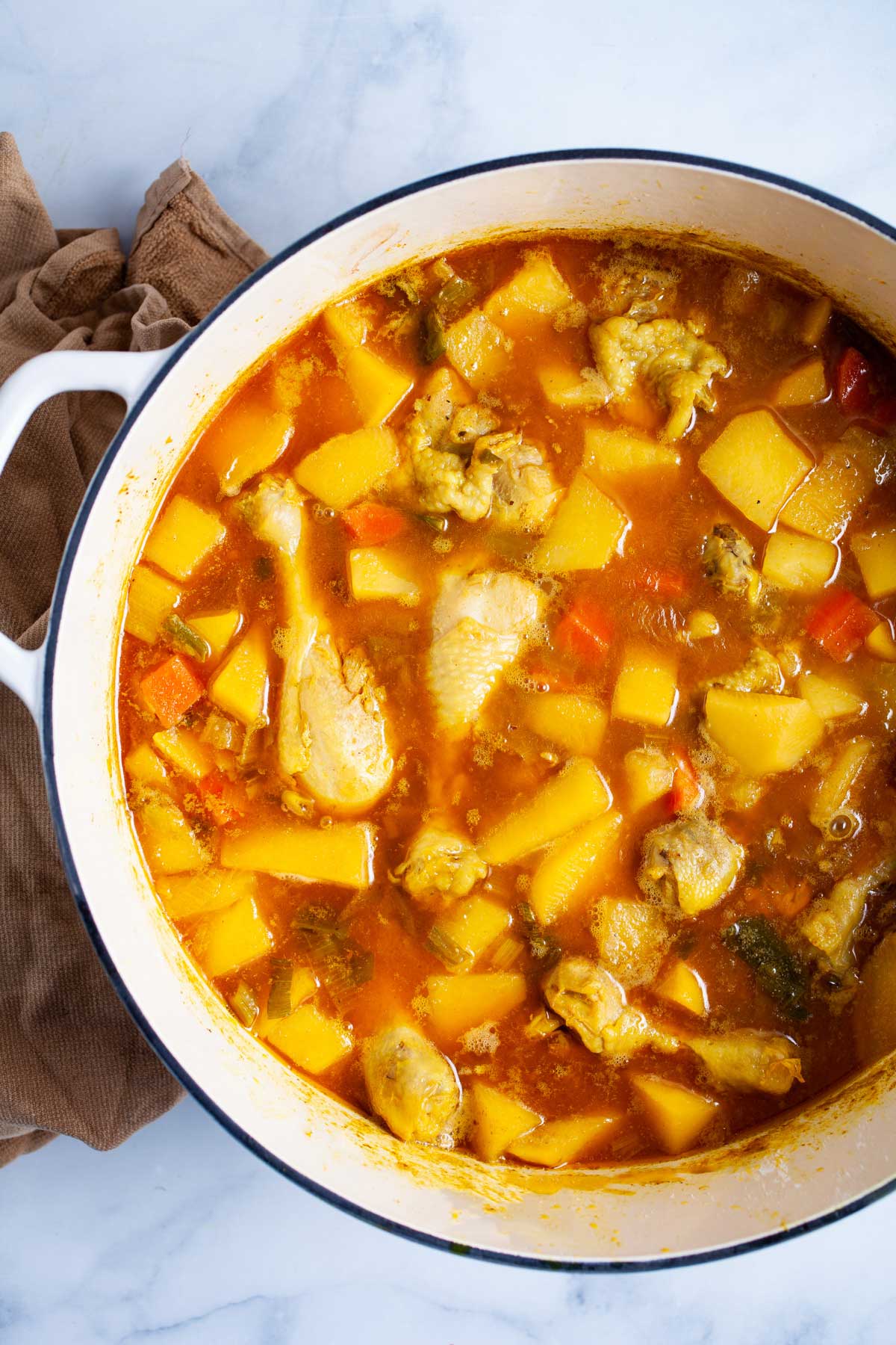 Chunky swede soup with chicken legs in a large pot.