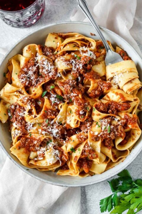 an overhead shot of bison bolognese on a bowl of pasta with a fork twirling some of the pasta.
