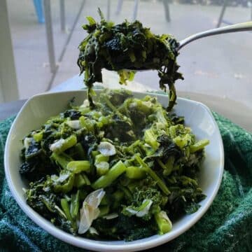 A fork taking a bite out of steamed broccoli rabe.