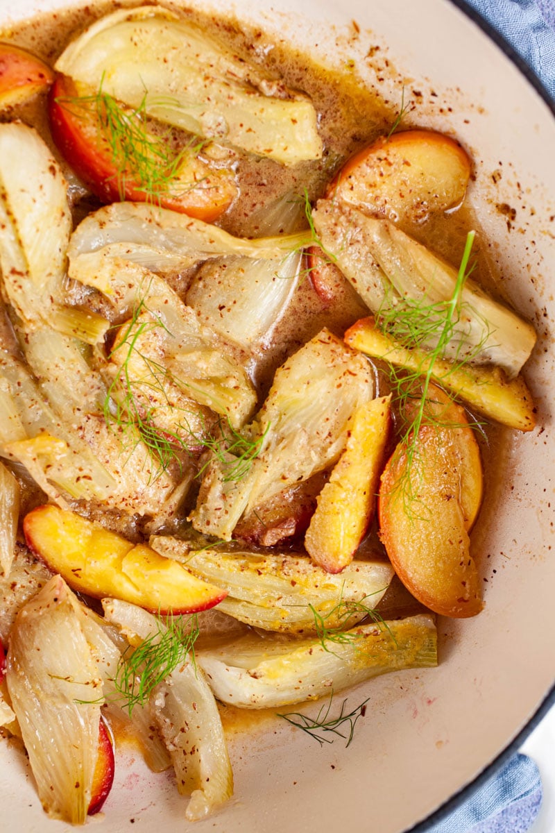 Braised fennel and peaches in a large pan with an almond flavored sauce.