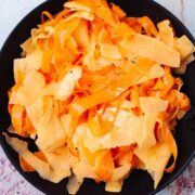 Seasoned raw carrot salad with apples on a serving plate.