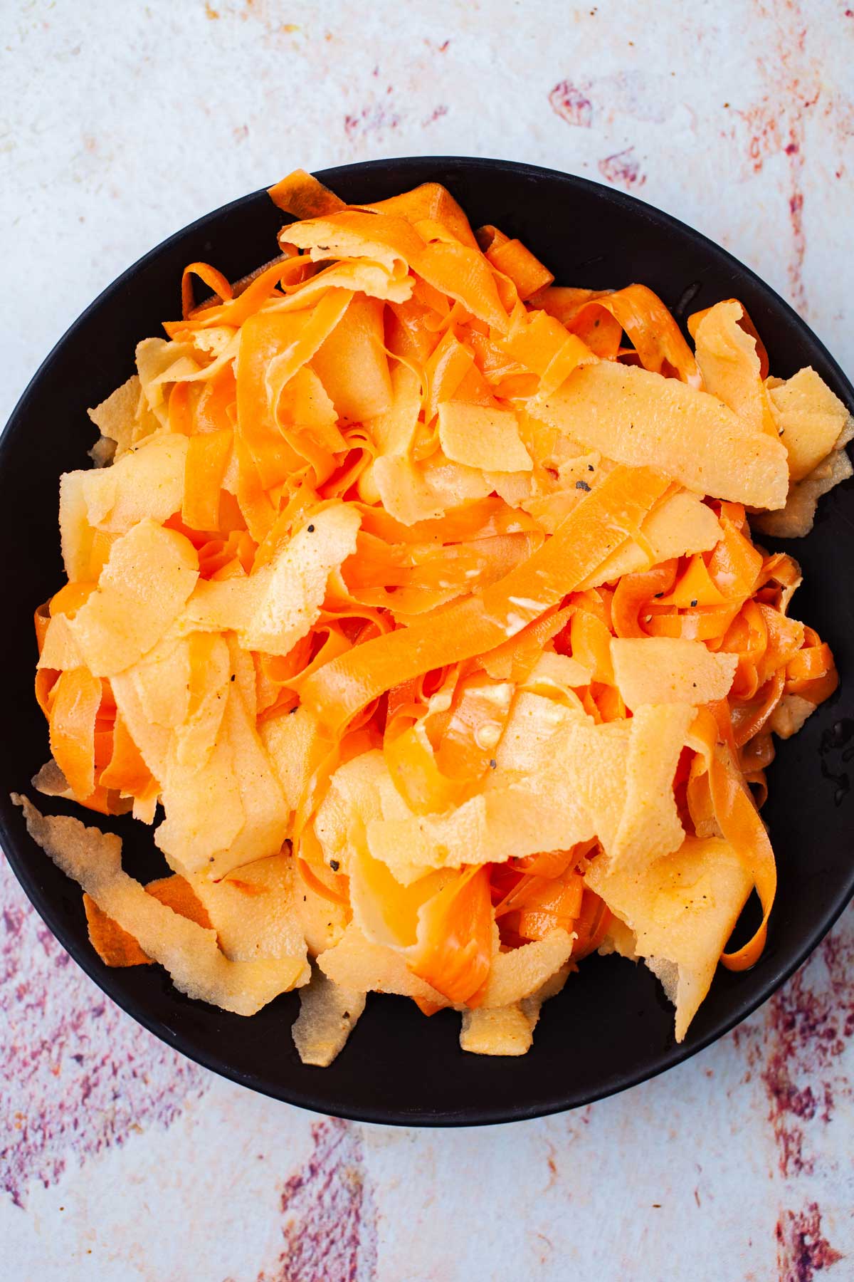 Seasoned raw carrot salad with apples on a serving plate.