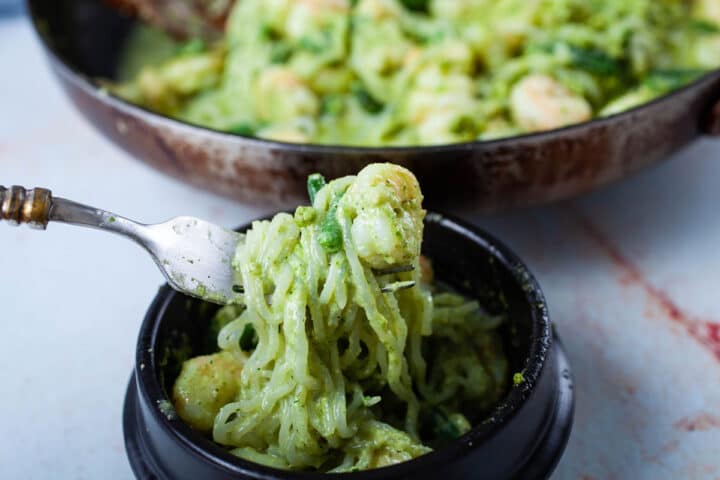 A fork lifting a large bite of Shirataki pesto noodles with a shrimp.