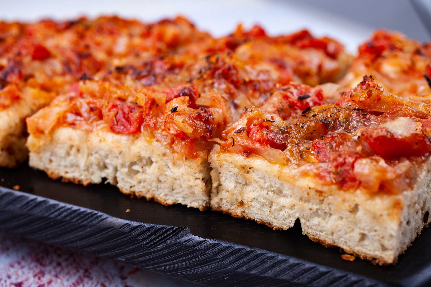 Squared shaped pizza pieces on a wooden board.