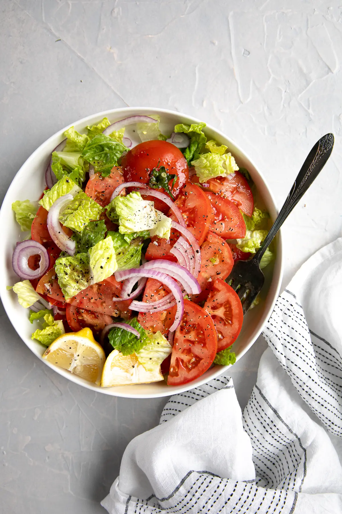 Fresh tomato salad with ice berg lettuce and onions in a bowl.