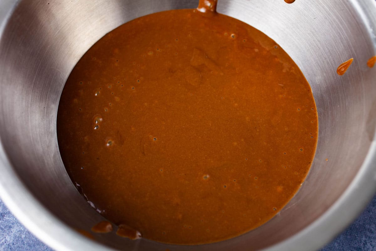 A brown wet batter in a stainless steel bowl.