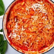 A large pan with spaghetti and a red tomato sauce with beans topped with cheese.